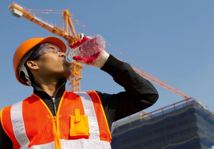 a construction worker is drinking water from a plastic bottle