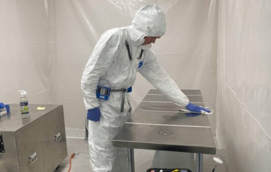 a man in a protective suit is cleaning a stainless steel table