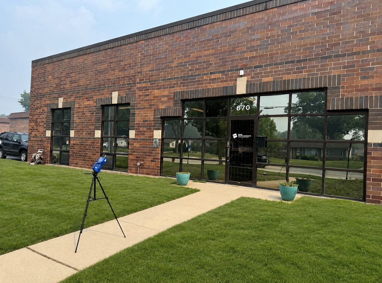RHP Risk Management industrial hygienist conducting outdoor AeroTrak real-time particle monitoring at the Elk Grove Village office under hazy, smoke-filled skies during the July 16, 2026 Canadian wildfire smoke event